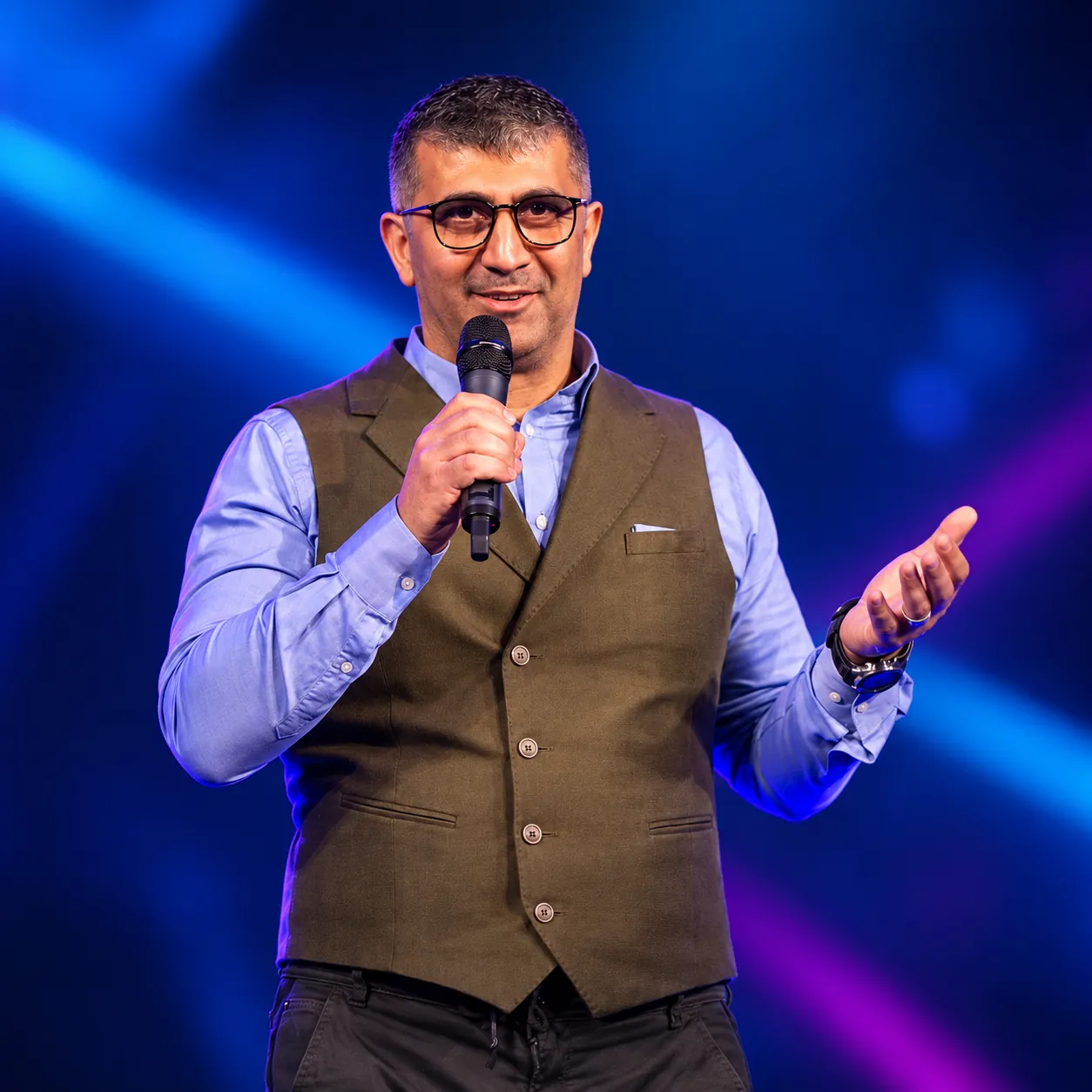 Sergey Usnunts speaking on stage with a microphone